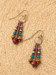 two pairs of beaded earrings sitting on top of a piece of woven material next to each other