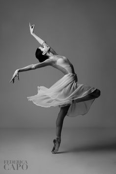 a woman in a white dress is dancing with her arms extended and legs spread out