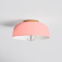 a pink ceiling light hanging from the ceiling with a white wall in the back ground