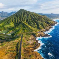 an aerial view of the ocean and mountains with a train on it's tracks