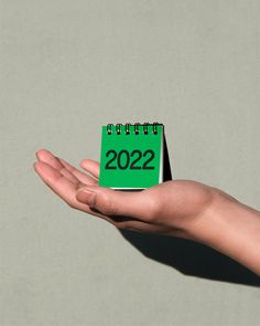 a person's hand holding a small green notepad with the date on it