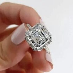 a woman's hand holding an engagement ring with a large diamond in the center