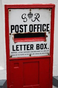 an old post office letter box on the side of a white building with red trim