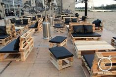 an outdoor seating area with wooden pallets and black cushions