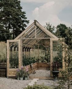 a small wooden greenhouse with plants growing inside