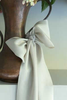 a vase with flowers and a white ribbon tied around it