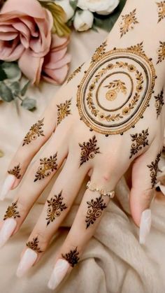 a woman's hand with henna on it and flowers in front of her