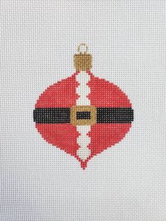 a cross stitch christmas ornament hanging on a white wall with red and black stripes