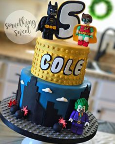 a three tiered cake decorated with legos and batman figures on top of it