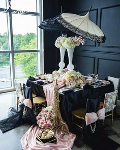 the table is decorated with pink and white flowers, an eiffel tower centerpiece, and black linens