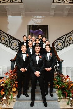 a group of men in tuxedos posing for a photo on the stairs at their wedding