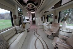 the inside of a bus with couches, chairs and tables in it's center