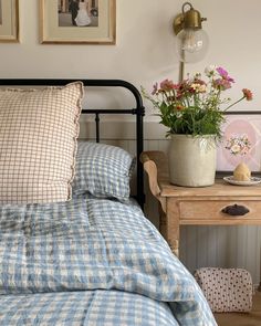 a bed with blue and white checkered bedspread next to a small wooden table