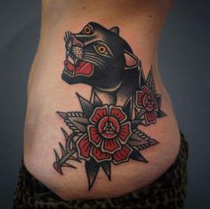 a black panther tattoo on the side of a woman's stomach with red flowers