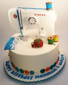 a birthday cake with a sewing machine on it's side and decorations around the edge