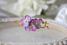 handmade micro crochet pansy flowers with pearl bangle  14K gold plasted adjustable bangle with miniature crochet flower.  These bangle are made with DMC cordonnet. They are lightweight and perfect for all day wear. bangle are gold plated brass from korea. If you have any questions, please reach out to us via messages before purchasing. *All items are handmade and may contain minor imperfections & a little color difference and variation between the picture and the actual item. But it doesn't make a big difference overall. Since this is a handmade item, we recommend handling these pieces with care. Do not bend or set heavy items on top of bangle.  ORDER  This item is made to order. Once order placed, I need 7 business days to prepare and ship the item. thank you! Adjustable 3d Flowers Jewelry For Wedding, Adjustable 3d Flowers Wedding Jewelry, Adjustable Flower Bangle For Wedding, Handmade Flower Shaped Elegant Bangle, Adjustable Purple Bangle Jewelry, Elegant Adjustable Purple Bangle, Floral Wrist Corsage, Victorian Adjustable Bangle - Gift, Elegant Adjustable Crochet Jewelry