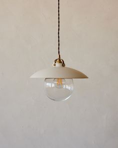 a light fixture hanging from a ceiling with a white wall behind it and a black cord