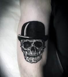 a man's arm with a skull wearing a top hat