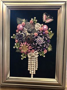 a framed painting with flowers and pearls on it