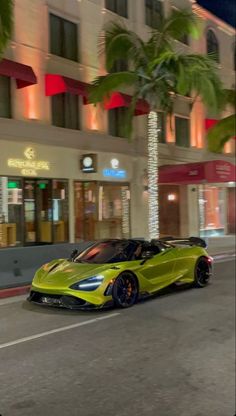 a yellow sports car is driving down the street at night in front of a hotel