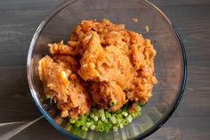 a glass bowl filled with fried food on top of a wooden table next to green peas