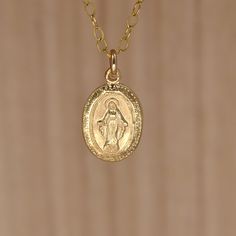 "Gold Virgin Mary Pendant Necklace. Miraculous Medal Necklace. A Miraculous Medal necklace in all 14K gold filled materials. The tiny pendant is understated and lightweight, yet sturdy. It measures approximately 12X9mm  (about 1/2 inch X 5/16 inch). It shows an image of the Virgin Mary crowned with a halo. The tiny letters around the circumference of the pendant read: \"O Mary conceived without sin pray for us who have recourse to Thee. \" What is gold-filled? Gold-filled jewelry contains almost 100 times more gold than gold-plated jewelry. Get the look and quality of karat gold at a fraction of the price.Find similar items in my shop: Browse my shop: ALLDANAE.etsy.com" Tiny Gold Pendant Necklace, Gold Tiny Round Pendant Necklace, Tiny Gold Round Pendant Necklace, Small Gold Round Pendant Necklace, Tiny Gold-plated Charm Necklaces, Tiny Gold Plated Charm Necklaces, Gold Charm Necklaces With Round Pendant, Gold Charm Necklace With Round Pendant, Tiny Gold Plated Gold Necklaces