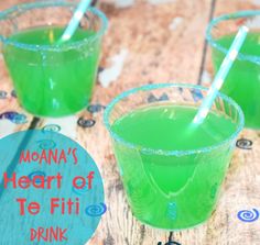 three glasses filled with green liquid sitting on top of a wooden table next to each other