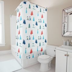 a bathroom with a toilet, sink and shower curtain covered in colorful christmas tree designs