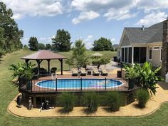 an above ground pool surrounded by grass and trees with a gazebo in the middle