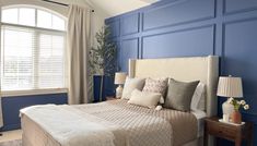 a bedroom with blue walls and white bedding