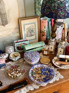 there are many plates on the table with different things in them, including candles and other items