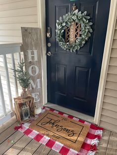 a welcome mat sitting on the front porch next to a blue door with a wreath