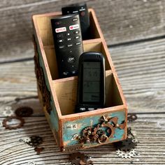 two cell phones in a wooden box on top of wood planks with gears around them