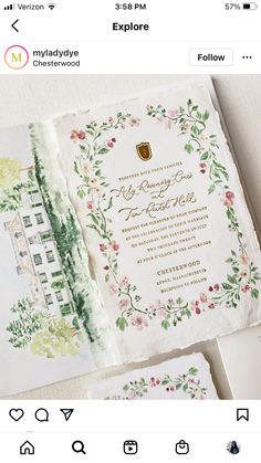 an open wedding card with flowers and leaves on it, sitting next to other cards