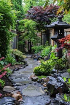 a garden with lots of rocks and plants around it, along with a lantern in the middle