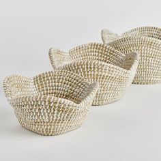 three woven baskets sitting side by side on a white surface