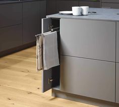 an open cabinet in the middle of a kitchen with two cups on top of it