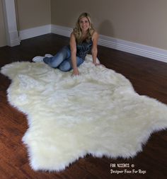 a woman is sitting on the floor in front of a white sheepskin area rug