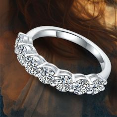 a diamond wedding band on top of a woman's head with long hair in the background