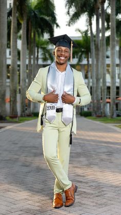 a man in a white suit and black hat is walking down the street with palm trees behind him