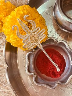 a metal bowl filled with red powder next to yellow flowers and a cake scooper