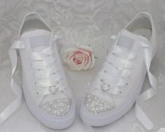 two white shoes with bows and a rose