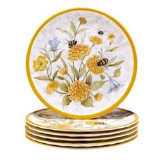 four plates with yellow and blue flowers on them are stacked next to each other in front of a white background