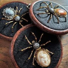 three spider brooches sitting on top of two black velvet covered boxes with buttons