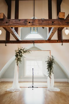 an indoor wedding ceremony setup with white drapes and greenery on the altars