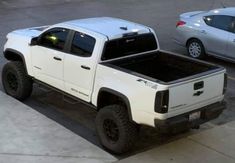 a white truck parked next to two silver cars