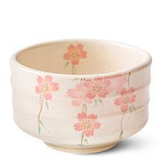 a white bowl with pink flowers painted on the outside and inside, sitting in front of a white background