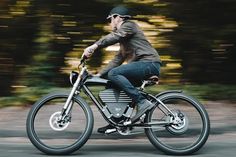 a man riding on the back of a motorcycle down a street with trees in the background