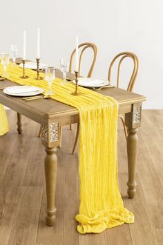 the table is set with yellow linens and place settings