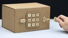 a cardboard box that has a key board attached to it, and a person's hand holding a pencil in front of it